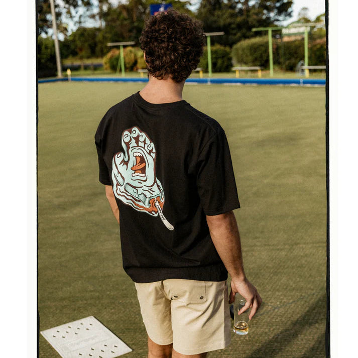 Person wearing a black t-shirt with a graphic design on the back, standing on a grassy field.