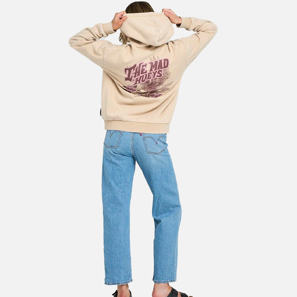 Person wearing a beige hoodie with text on the back and blue jeans, standing against a white background