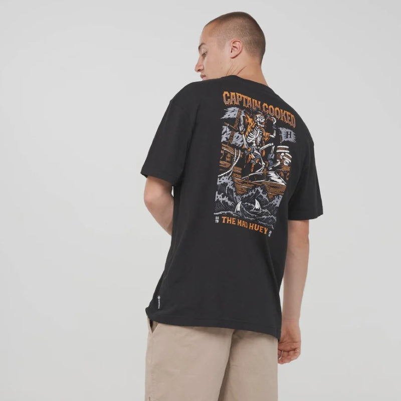 A man shown from the back wearing a black Captain graphic t-shirt, beige cargo shorts, black socks, and black Nike sneakers against a light gray studio background.