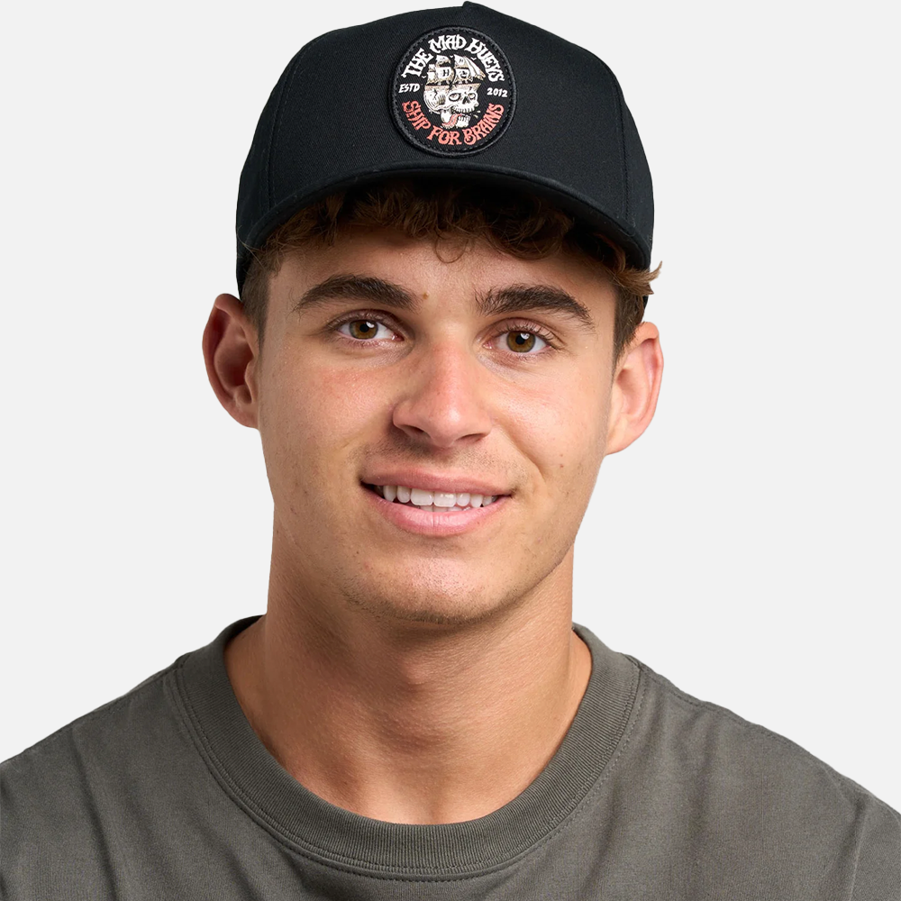 Man wearing a black cap with a logo on a plain background