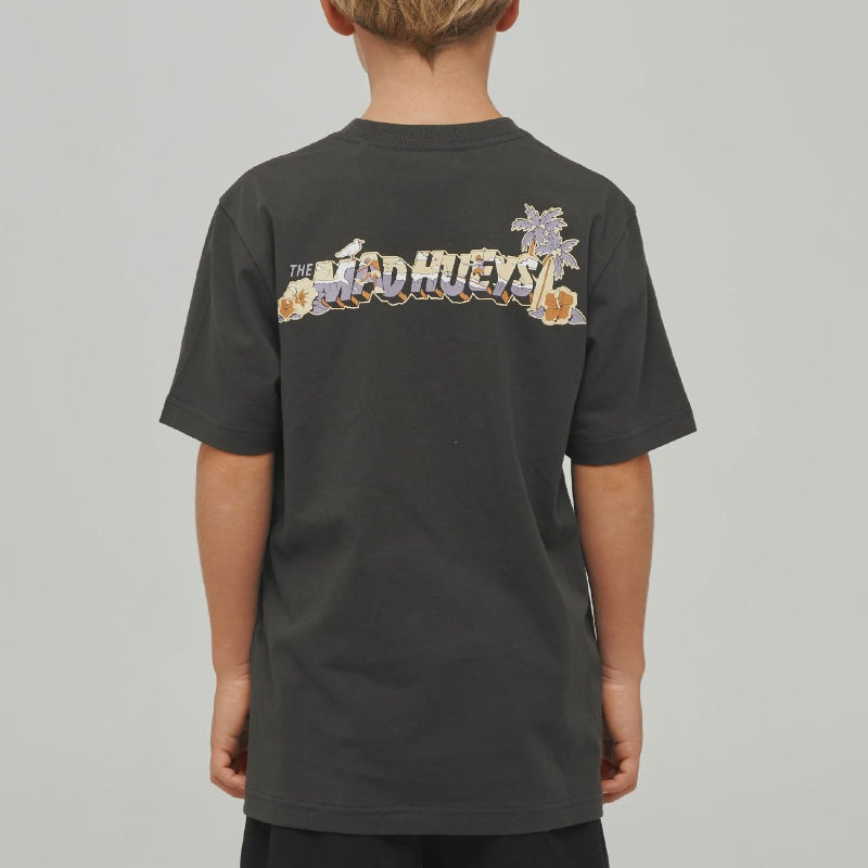 A child viewed from behind wearing a dark charcoal gray t-shirt with a colorful graphic print on the back. The graphic features the text 'THE MAD HUEYS' in a stylized font with a purple flower and orange details.