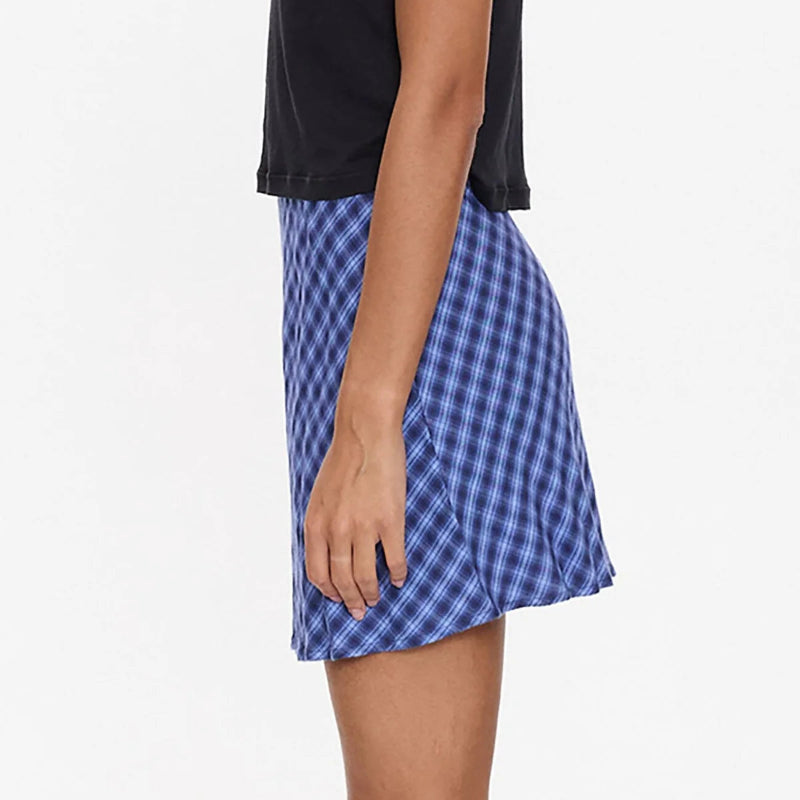 Person wearing a black top and blue checkered skirt on a white background