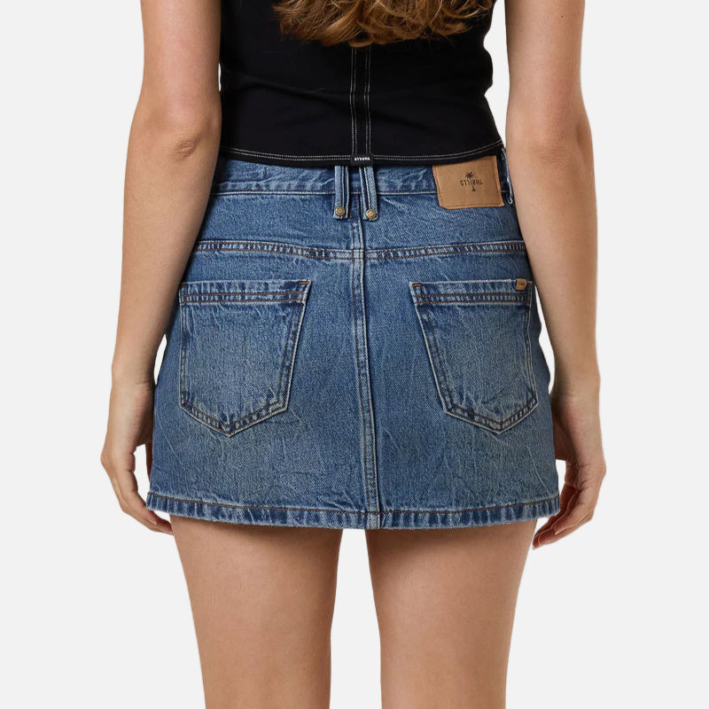 Person wearing a black top and blue denim skirt on a plain background
