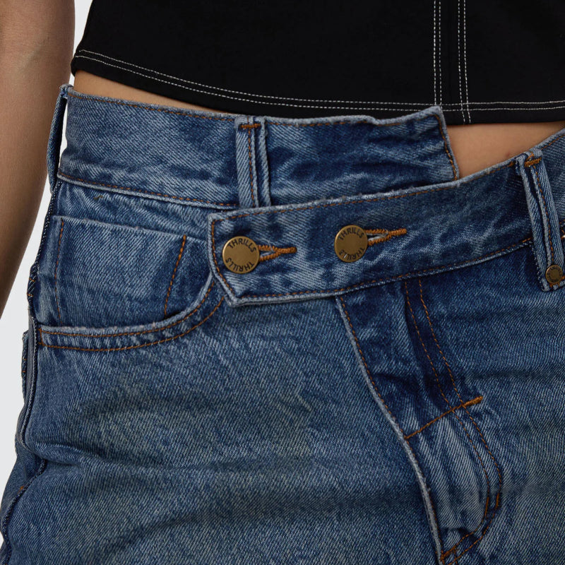 Close-up of blue jeans with a black top on a plain background