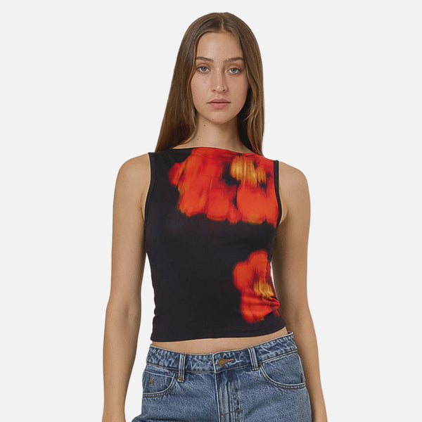 Woman wearing a black tank top with red and red flower design and blue jeans on a gray background