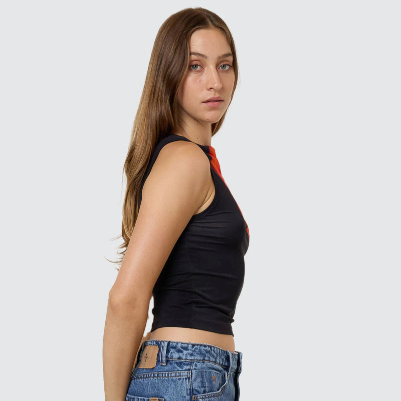 Woman wearing a black tank top and blue jeans on a light gray background