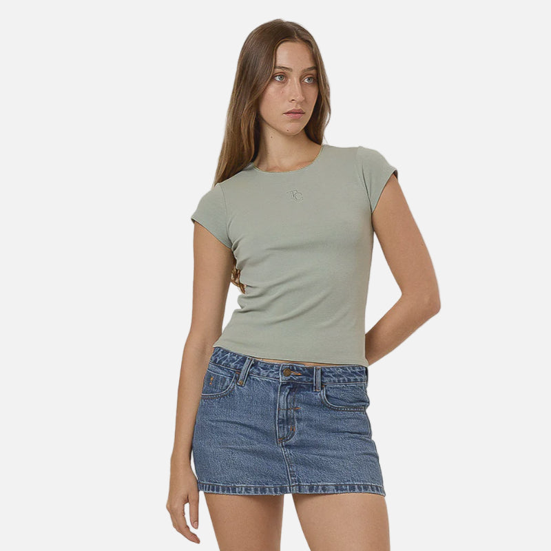 Woman wearing a green t-shirt, blue denim skirt, and black boots on a white background