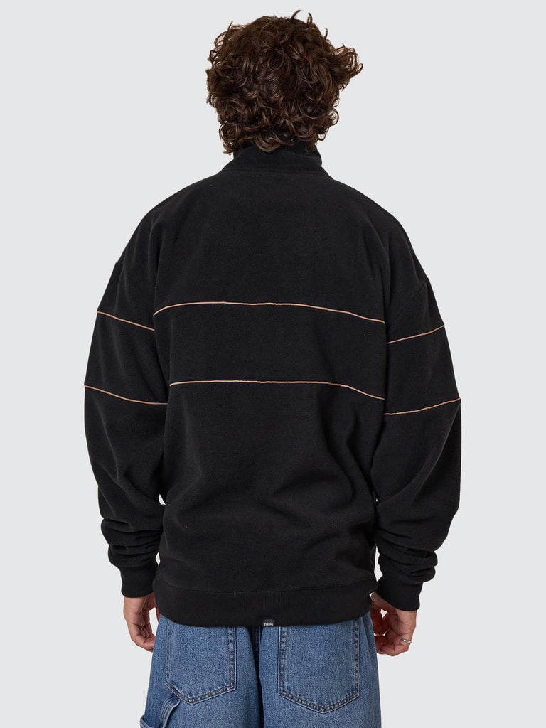 Person wearing a black pullover with stripes on the back against a light gray background