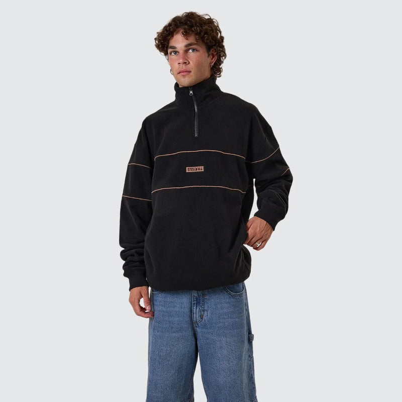 Person wearing a black pullover with a brand logo on a white background