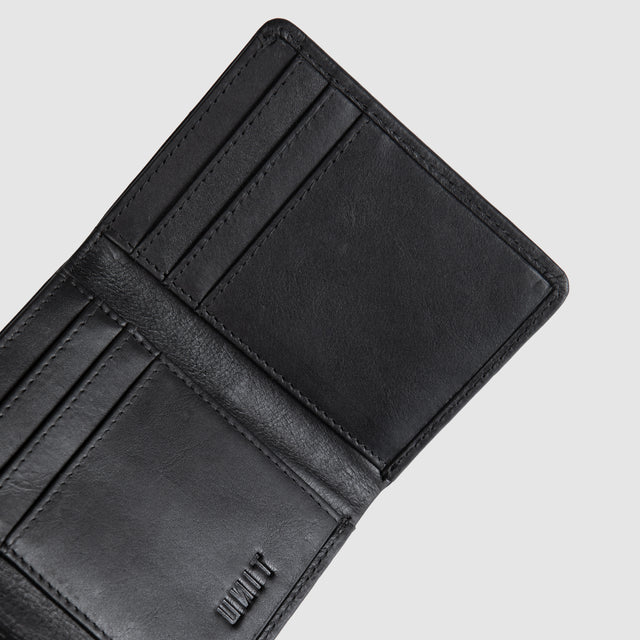Close-up of an open black leather wallet showing interior card slots and a small embossed logo on a light gray background.