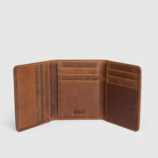 An open brown leather bi-fold wallet showing its interior card slots, pockets, and the embossed brand name 'UNIT' on the center panel, set against a light gray background.