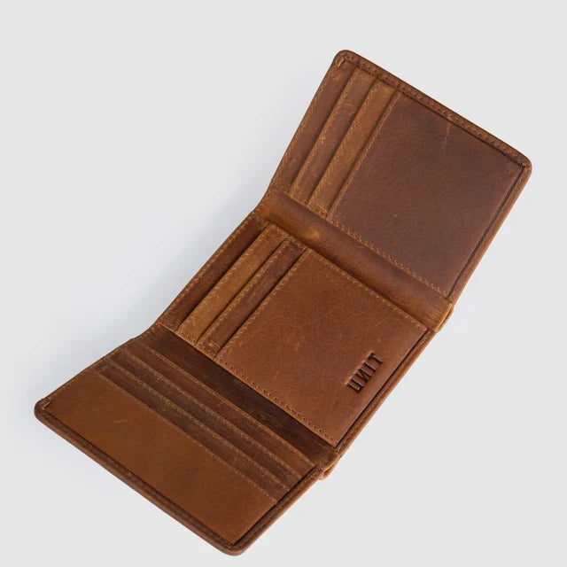 An open brown leather bifold wallet with multiple card slots and a vertical pocket, shown on a light gray background. The brand name 'UNIT' is embossed on the interior.