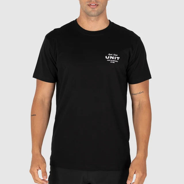 A man wearing a black short-sleeve crewneck t-shirt with a small white graphic on the left chest that reads 'UNIT' and 'THE NEW ERA', photographed against a solid light gray background.