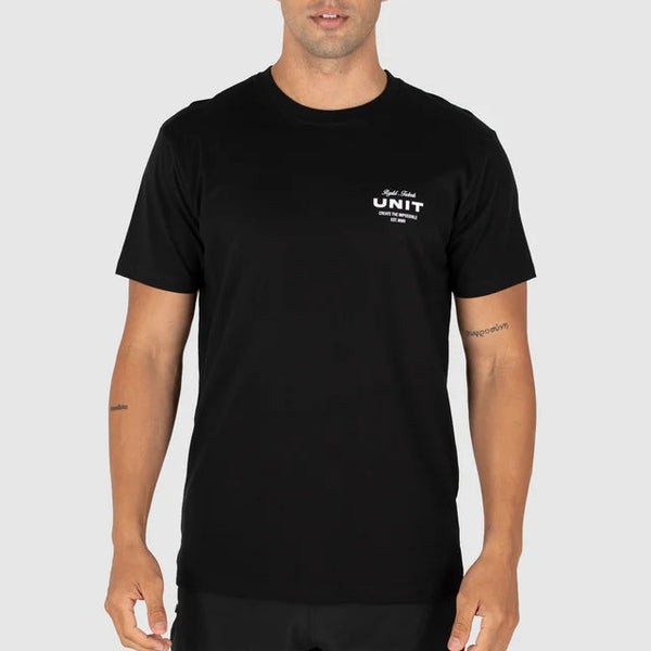 A man wearing a black short-sleeve crewneck t-shirt with a small white graphic on the left chest that reads 'UNIT' and 'THE NEW ERA', photographed against a solid light gray background.