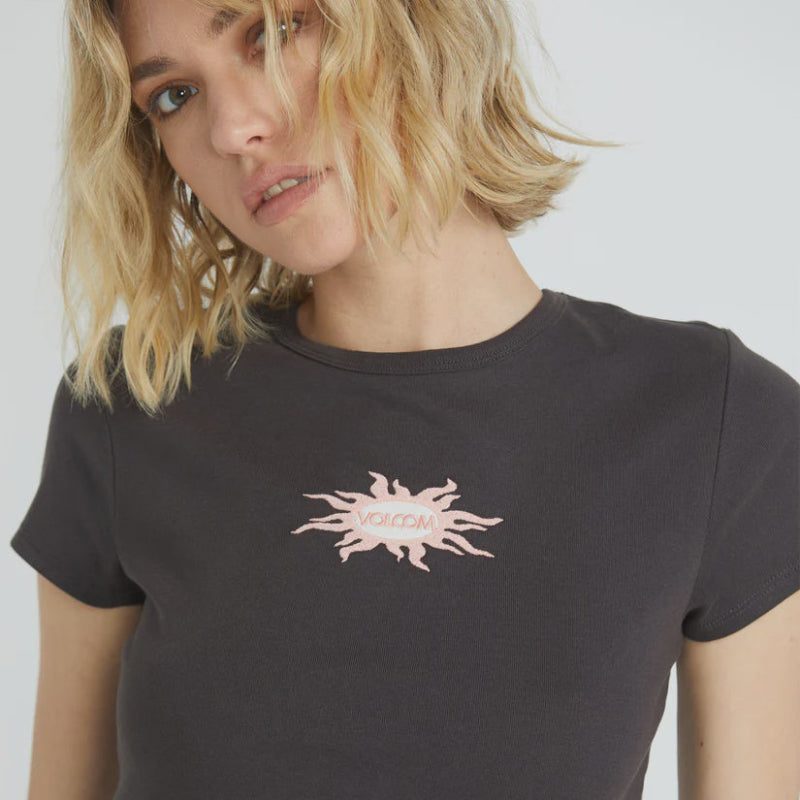 Person wearing a black t-shirt with a pink logo on a plain background