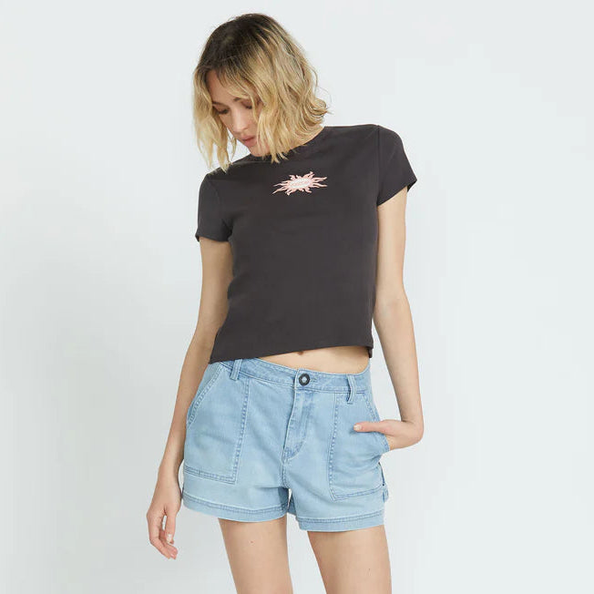 Woman wearing a black t-shirt with a graphic design and light blue denim shorts on a white background