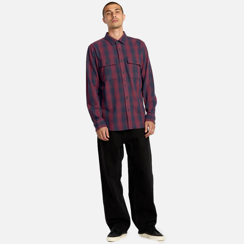 Man wearing a red and blue plaid shirt with black pants on a white background
