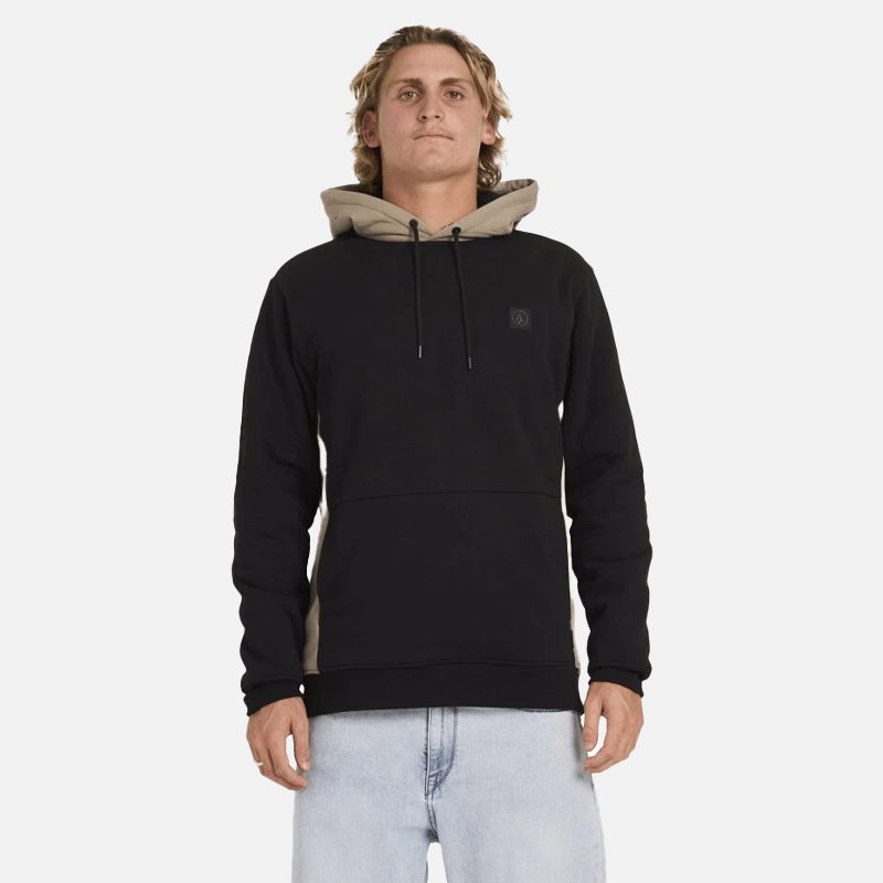 Person wearing a black hoodie with beige accents on a white background