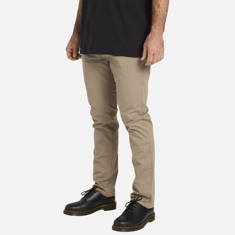 Person wearing beige pants and black shoes on a white background