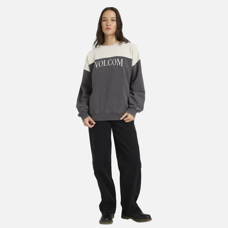 Person wearing a Volcom sweater and black pants on a white background