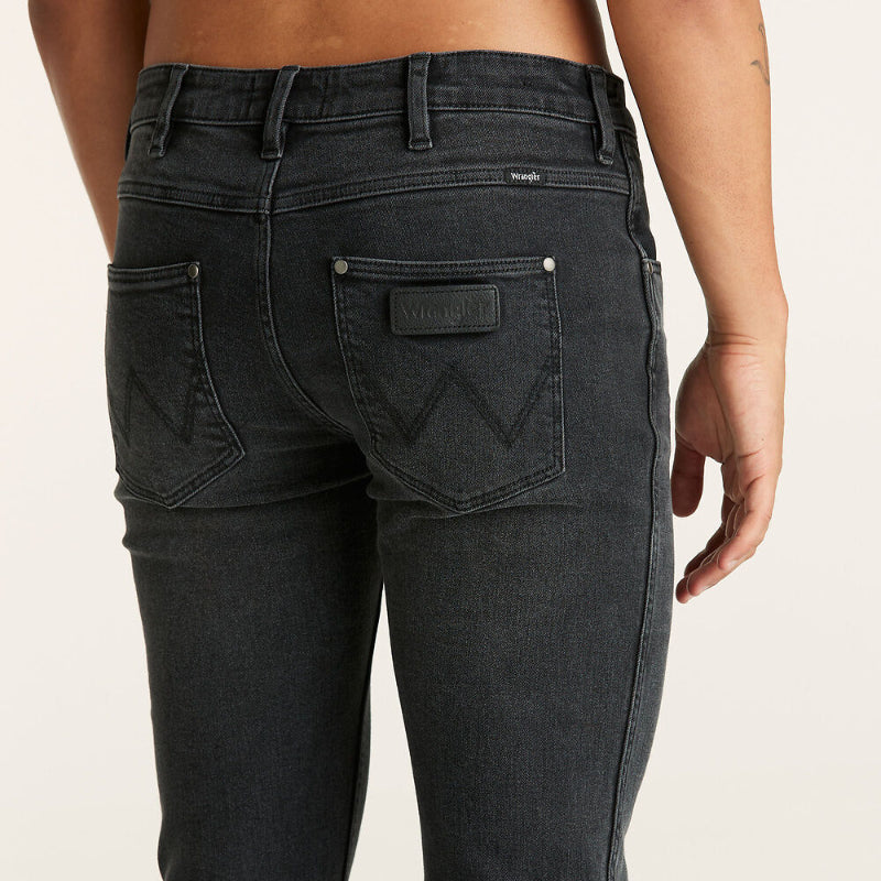 Black jeans with a brand logo on a beige background
