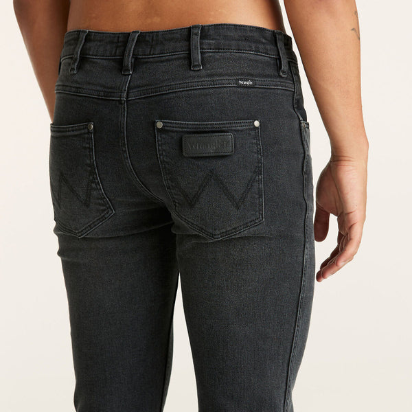 Black jeans with a brand logo on a beige background